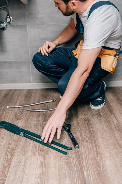 Partial view of male plumber taking gas wrench for repairing broken sink in bathroom — Stock Photo