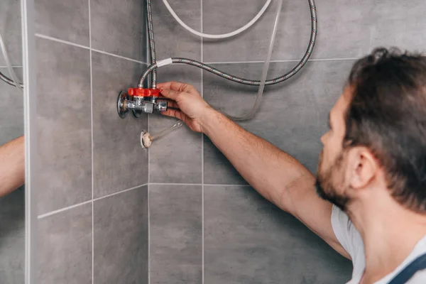 Selective focus of male plumber repairing electric boiler in bathroom — Stock Photo