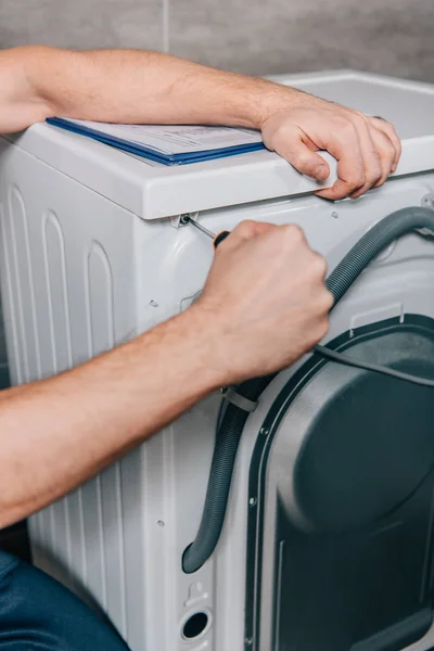 Обрізане зображення чоловічої майстрині, що ремонтує пральну машинку у ванній — стокове фото