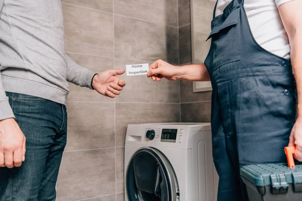 Abgeschnittenes Bild eines männlichen Heimwerkers, der dem Besitzer im Badezimmer eine Karte mit Schriftzug gibt — Stockfoto