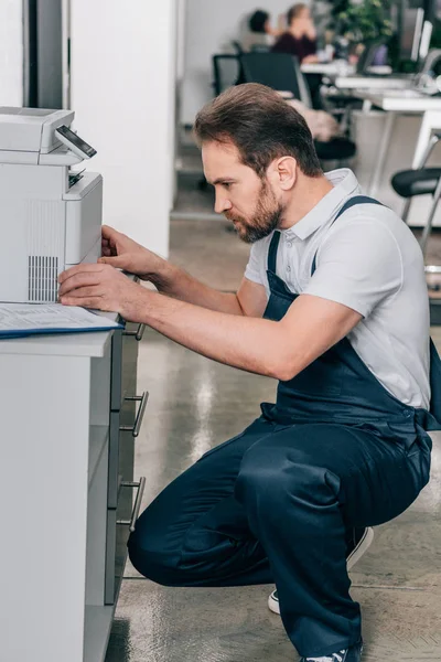 Vista laterale del tuttofare maschio che ripara la fotocopiatrice nell'ufficio moderno — Foto stock