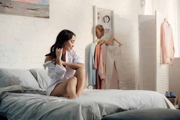 Attraente seducente asiatico donna in bianco camicia seduta su letto in il mattina — Foto stock