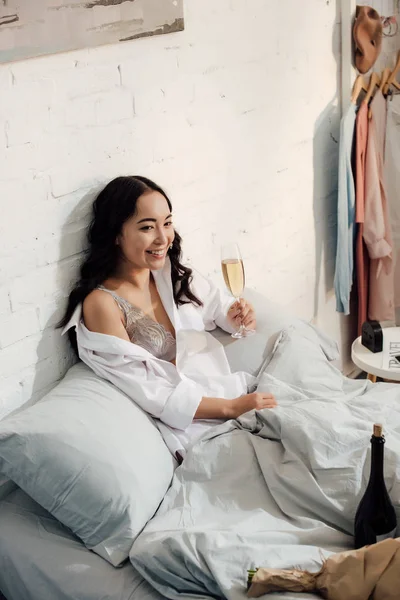 Вид под высоким углом на красивую счастливую девушку, пьющую вино в постели — стоковое фото