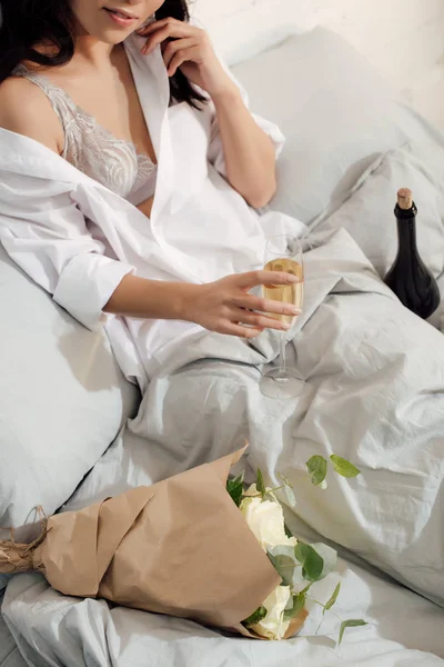 Cropped shot of beautiful young woman holding glass of champagne in bed — Stock Photo