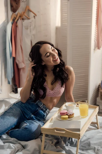 Bela feliz jovem asiático mulher sentado no cama e desfrutar de pequeno-almoço — Fotografia de Stock