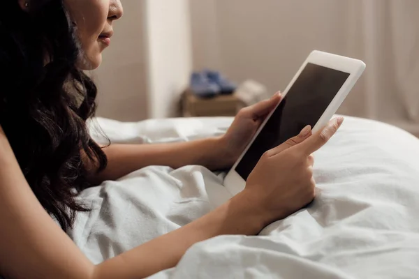 Обрезанный снимок привлекательной девушки, лежащей на кровати и с помощью цифрового планшета с чистым экраном — стоковое фото