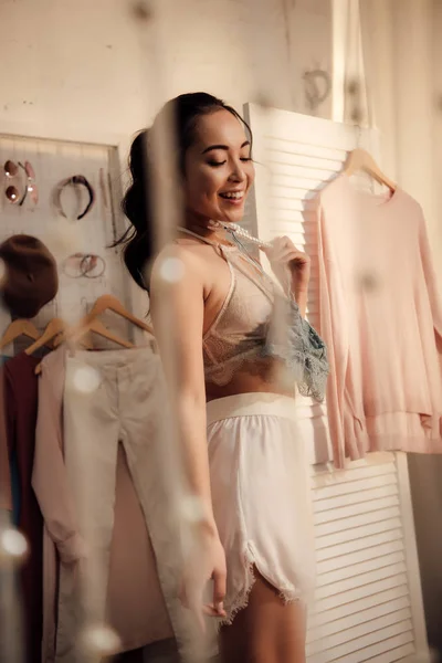 Beautiful smiling young woman choosing what to wear in wardrobe — Stock Photo