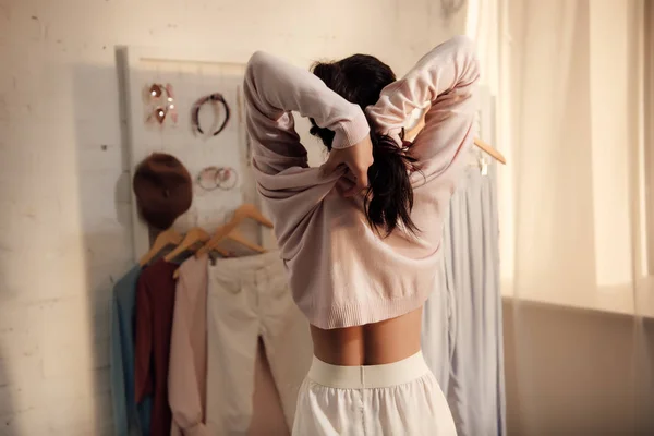 Back view of young woman putting on stylish sweater at home — Stock Photo