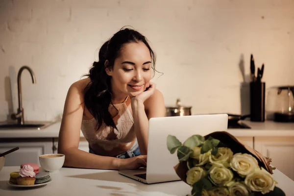 Sonriendo joven asiático mujer usando laptop en casa - foto de stock