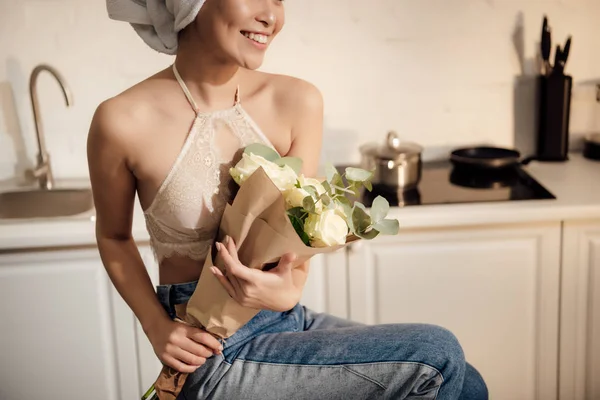 Foto recortada de chica sorprendida con toalla en la cabeza sosteniendo ramo de rosas blancas en casa - foto de stock