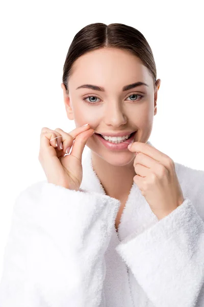 Woman in white bathrobe flossing teeth and looking at camera isolated on white — Stock Photo