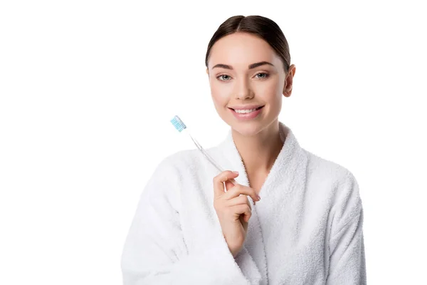 Bela mulher sorridente em roupão de banho branco segurando escova de dentes isolada no branco — Fotografia de Stock