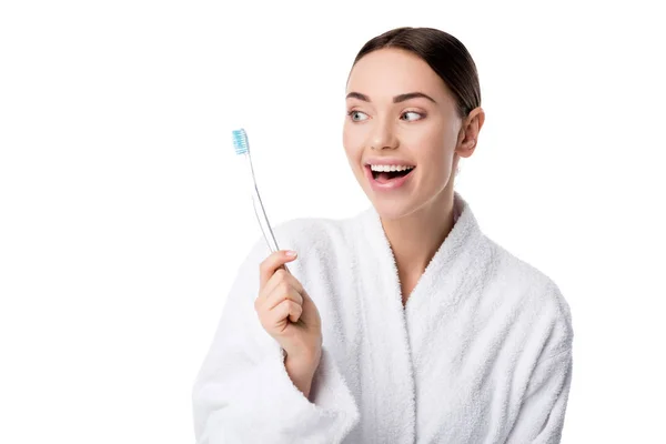 Bela mulher feliz em roupão de banho branco segurando escova de dentes isolada no branco — Fotografia de Stock