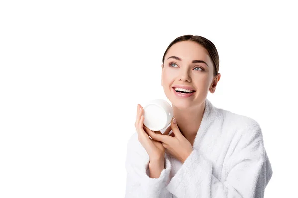 Cheerful woman in bathrobe holding face cream isolated on white — Stock Photo