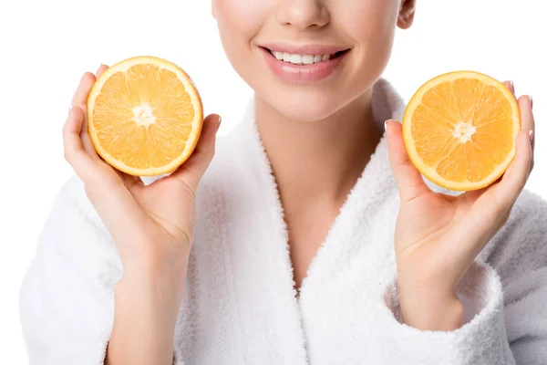 Vista parcial de mujer sonriente en albornoz blanco sosteniendo naranjas aisladas en blanco - foto de stock