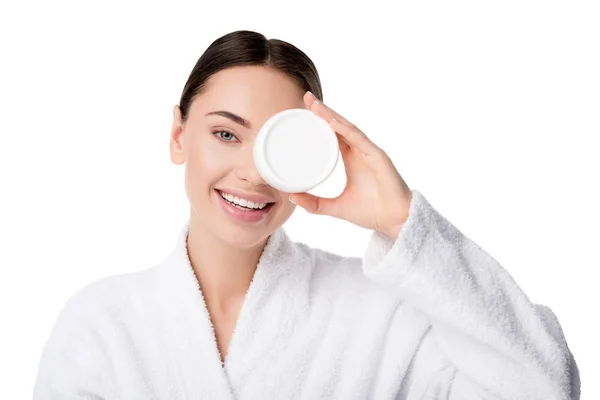 Beautiful woman in bathrobe holding moisturizing cream in front of face isolated on white — Stock Photo