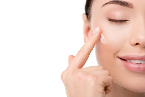 Vista recortada de la mujer aplicando crema hidratante para la cara aislada en blanco - foto de stock