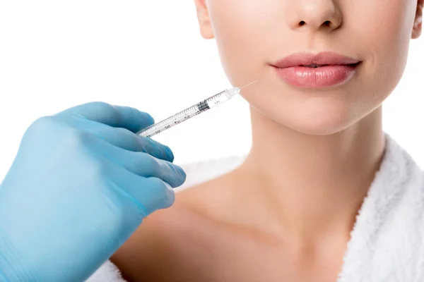 Vista parcial del médico en guante de látex administrando inyección de labio con jeringa a una mujer aislada en blanco - foto de stock