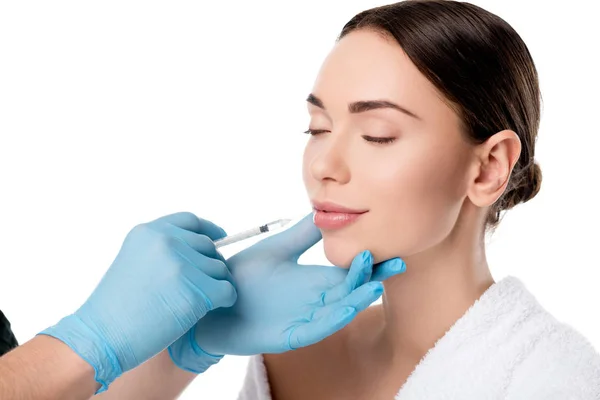 Doctor en guantes de látex dando inyección de labio con jeringa a mujer atractiva aislada en blanco - foto de stock