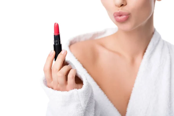 Vista recortada de la mujer en albornoz haciendo pucheros labios y sosteniendo lápiz labial rojo aislado en blanco - foto de stock