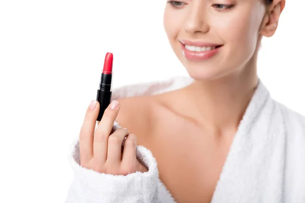 Mujer en albornoz sosteniendo lápiz labial rojo aislado en blanco - foto de stock