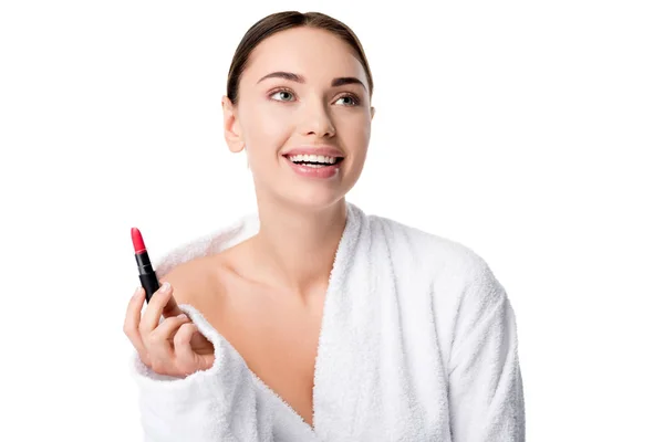 Beautiful cheerful woman in bathrobe holding red lipstick isolated on white — Stock Photo