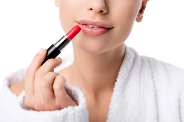 Vista recortada de la mujer en albornoz aplicando lápiz labial rojo aislado en blanco - foto de stock