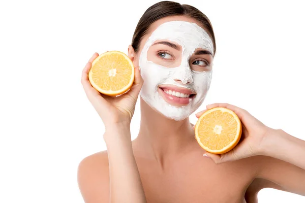 Bela mulher sorridente com máscara facial cuidados da pele segurando laranjas isoladas em branco — Fotografia de Stock