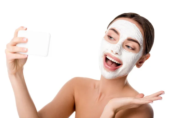 Femme heureuse avec masque de soins de la peau du visage prenant selfie sur smartphone isolé sur blanc — Photo de stock