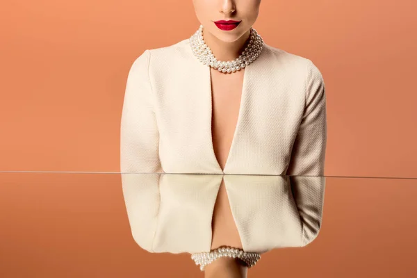 Обрізаний вид жінки в перловому намисті з дзеркальним відображенням ізольовані на помаранчевому — стокове фото
