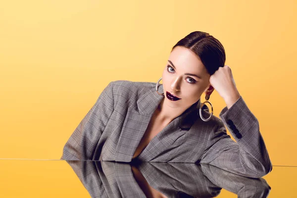 Attractive glamorous woman in formal wear with mirror reflection looking at camera isolated on yellow — Stock Photo