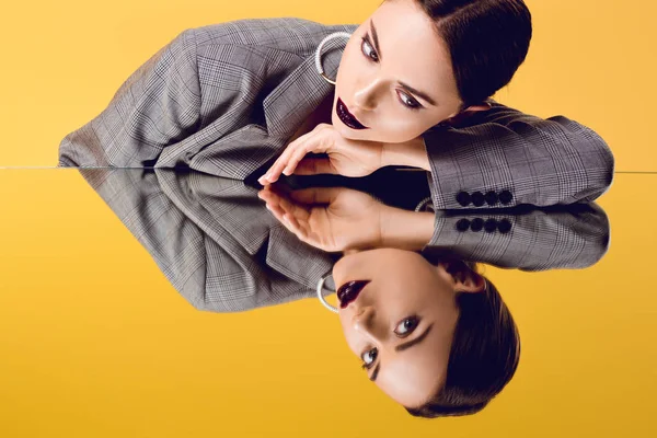 Beautiful glamorous woman in formal wear looking at mirror reflection isolated on yellow — Stock Photo