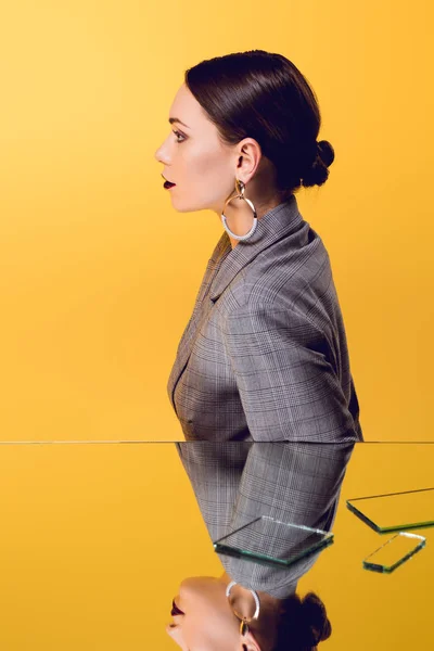 Красива гламурна жінка в офіційному одязі з дзеркальним відображенням ізольована на жовтому — стокове фото