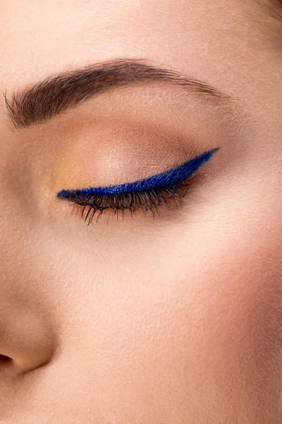 Partial view of closed female eye with blue eyeliner and perfect skin — Stock Photo