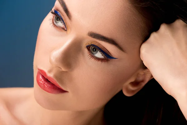 Retrato de hermosa mujer pensativa con maquillaje glamoroso aislado en azul - foto de stock