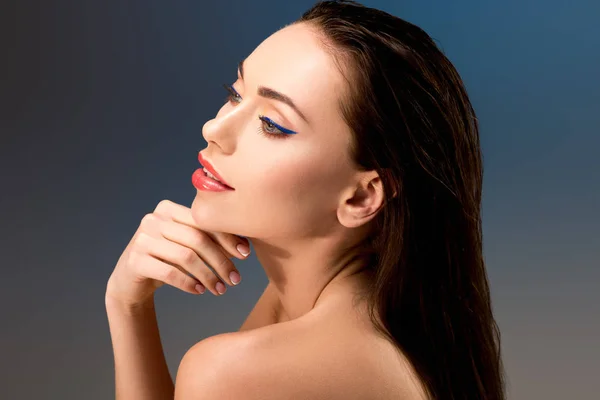 Portrait of beautiful woman with glamorous makeup touching face and looking away — Stock Photo