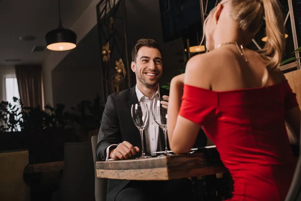 Guapo novio mirando novia en rojo vestido durante la cena - foto de stock