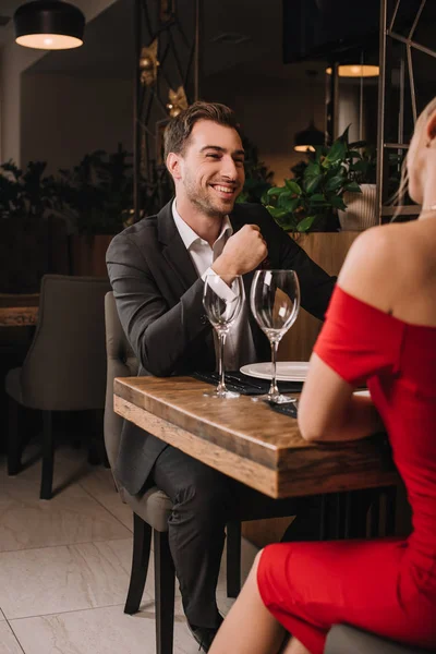 Bonito namorado olhando e sorrindo para namorada no vestido vermelho — Fotografia de Stock