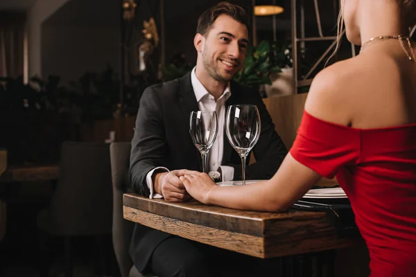 Schöner Freund lächelt und hält Hand seiner Freundin im roten Kleid — Stockfoto