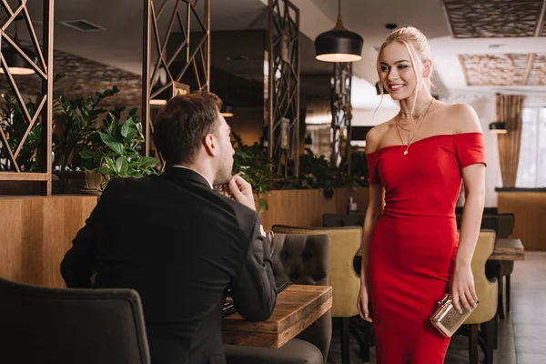 Парень смотрит на привлекательную улыбающуюся девушку в красном платье — стоковое фото