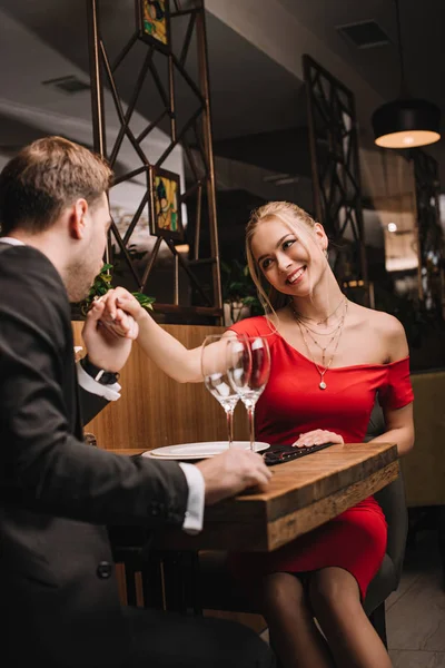 Novio en traje besos mano de atractiva novia - foto de stock