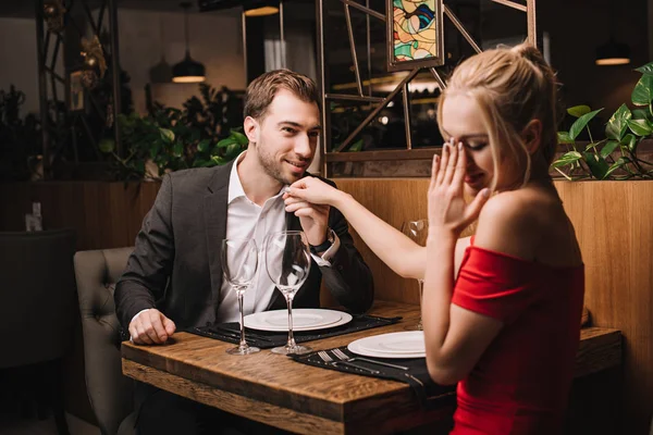 Bonito namorado no terno beijando mão de namorada no vestido vermelho — Fotografia de Stock