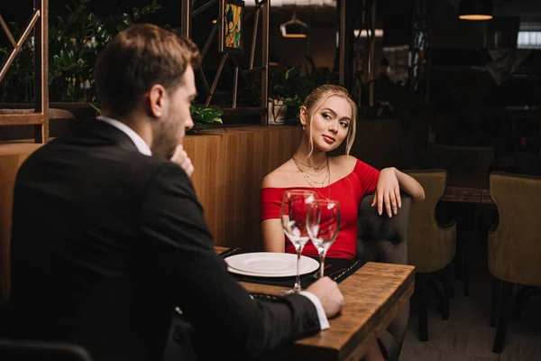 Attractive girlfriend in red dress looking at boyfriend — Stock Photo