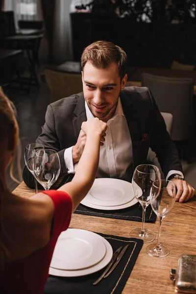 Handsome boyfriend in suit kissing hand of girlfriend in red dress — Stock Photo