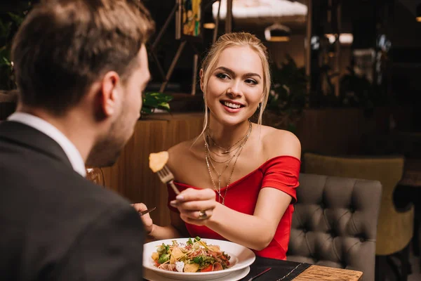 Alegre novia alimentación novio en restaurante - foto de stock