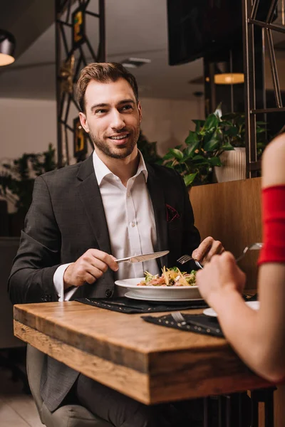 Hombre guapo mirando a su novia mientras cenaba en el restaurante - foto de stock