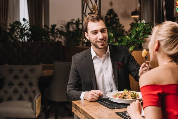 Schöner Freund füttert Mädchen mit frischem Salat im Restaurant — Stockfoto