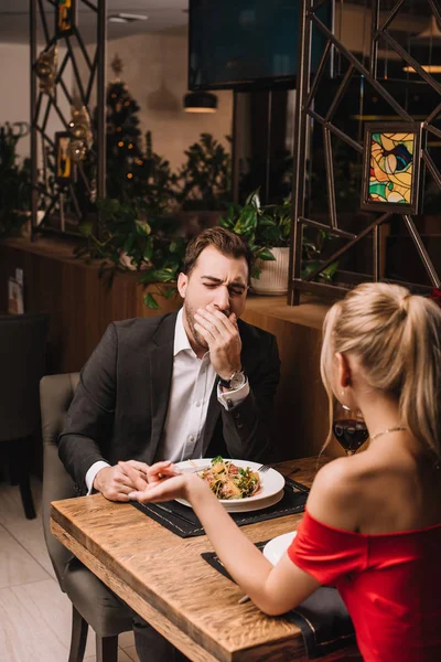 Boyfriend yawning while listening girl in restaurant — Stock Photo