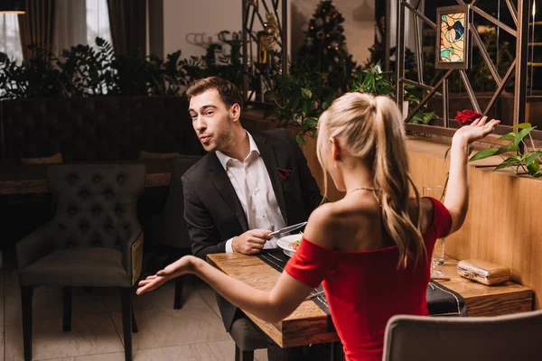 Sorprendido hombre sentado en restaurante con mujer rubia - foto de stock