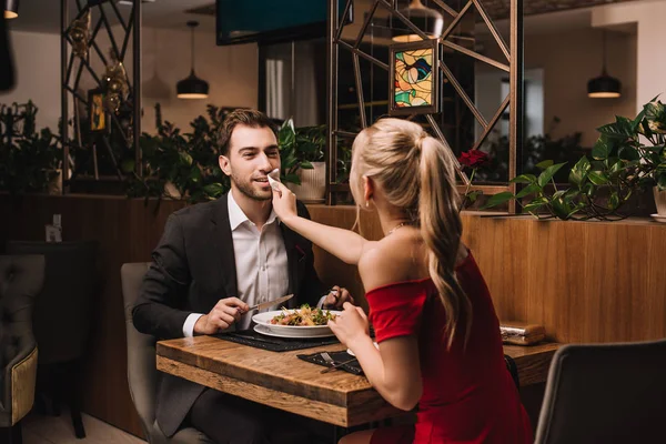 Girlfriend wiping mouth of handsome boyfriend with napkin in restaurant — Stock Photo